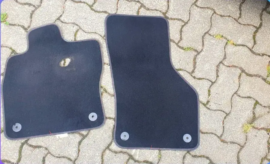 Dieselben Fußmatten nach der Reinigung, Gewebe wieder durchgehend schwarz